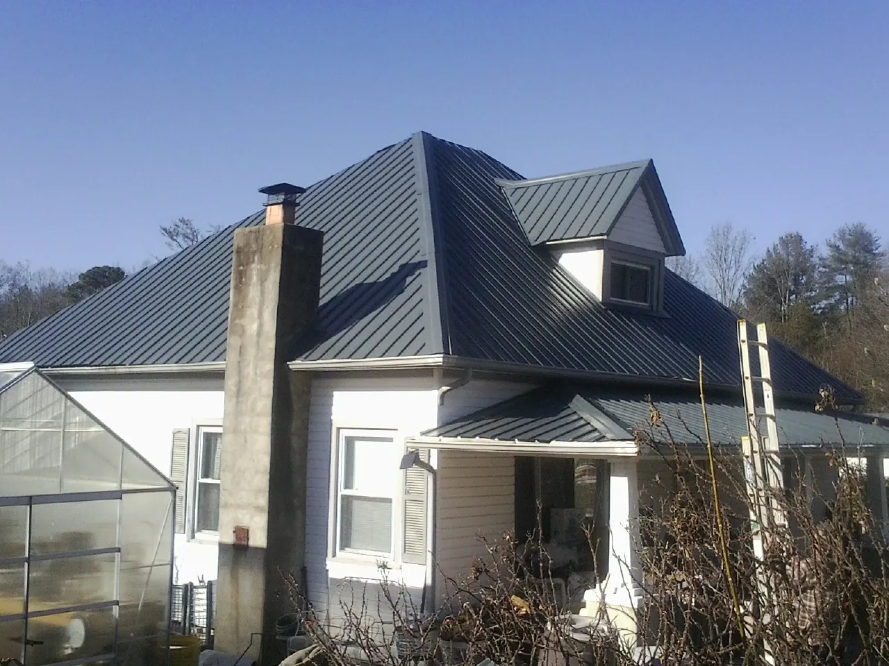 Dark blue standing seam metal roof on a white farmhouse with dormer — Slate & Tile Roof Repair by Roofing Brothers in Big Bar
