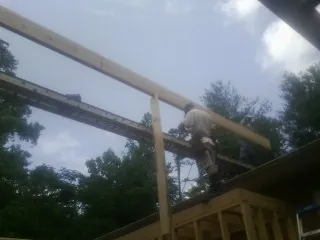 Carpenter setting a ridge beam over a new addition frame — Ice Dam Removal by Roofing Brothers in Big Bar