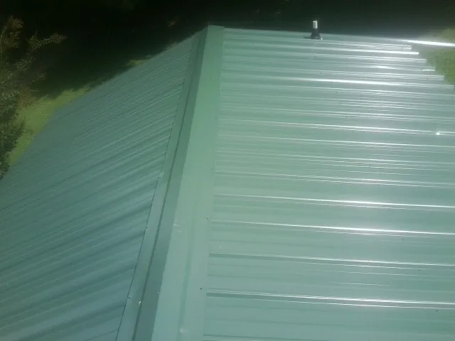 New green metal panels meeting at the ridge of a roof — Flat Roof Repair work by our crew in Big Bar