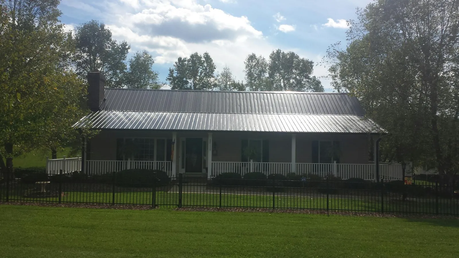 Gray metal roof on a brick ranch with a full width front porch — Gutter Guard Installation work by our crew in Big Bar