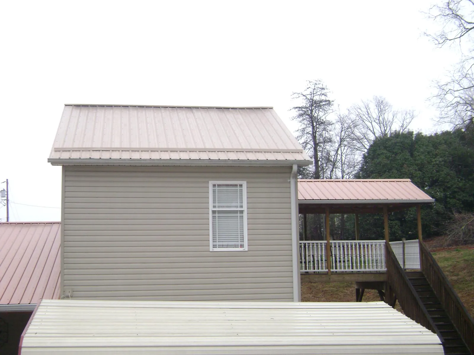 Tan metal roofs on a two story addition and attached porch, from a Roof Replacement job in Big Bar