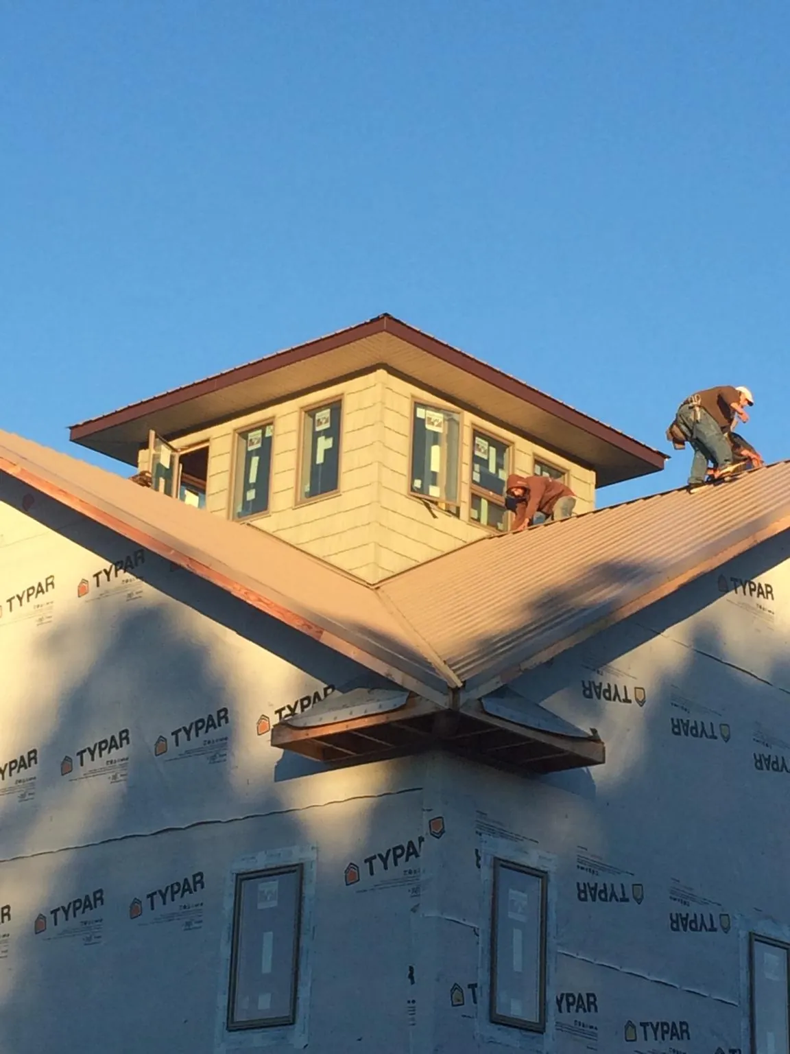Roofers working around a rooftop cupola on a new metal roof at sunset — Roof Waterproofing in Big Bar by Roofing Brothers